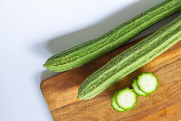 Fresh Angled luffa (Ribbed Gourd) fruits with sliced on wooden cut. nutrition ingredient. top view