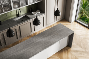 Modern kitchen interior with minimalist island, wood chevron flooring, and green backsplash seen...
