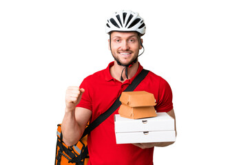 Young delivery man taking a takeaway food over isolated chroma key background celebrating a victory...