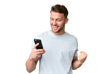 Young handsome caucasian man over isolated chroma key background using mobile phone and doing...