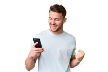 Young handsome caucasian man over isolated chroma key background using mobile phone and doing victory gesture