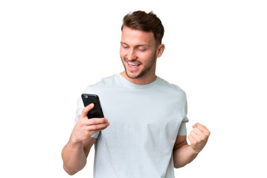Young handsome caucasian man over isolated chroma key background using mobile phone and doing victory gesture