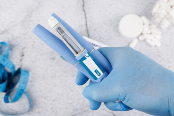Cement surface with top view of semaglutide injection pen held by blue gloved hand, modern layout for health and therapy media