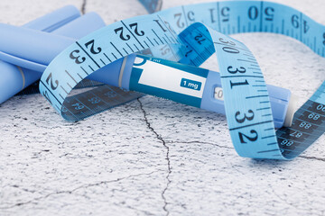 Semaglutide injection pens with blue measuring tape on concrete surface, top view concept for diabetes, obesity and medical therapy