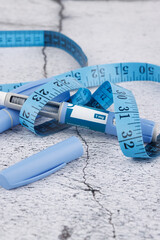 Flat lay of semaglutide injection pens and blue dressmaker tape on cement surface, medical concept for diabetes and weight treatment