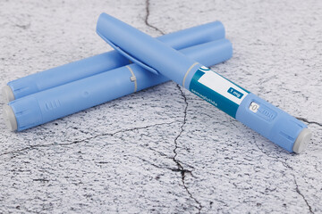 Top view of semaglutide injection pens and dressmaker tape on rough concrete, medical and wellness...