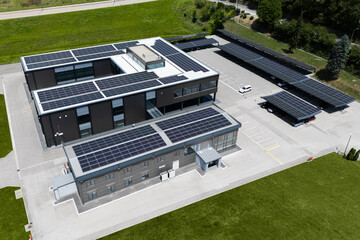 Aerial view of building with solar panels on a roof and parking space with solar canopies