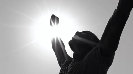 Un homme avec les bras levés célèbre sa victoire sous un rayon de soleil