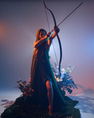 dramatic portrait of female model figure wearing green fantasy fae cloak costume, holding archery...