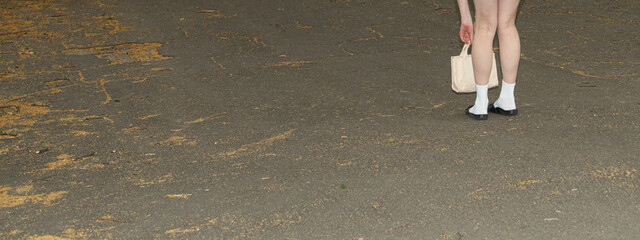 A person bends down to gather fallen leaves along a sidewalk in the evening, showcasing the...