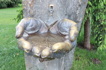 An artistic sculpture of hands gently holding water, symbolizing connection and harmony