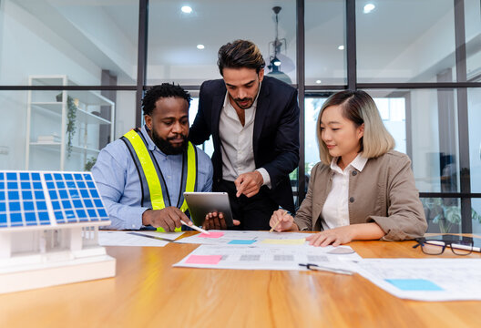 team of multiethnic coworker meeting on solar roof system project with solar panel house model, responsibility of green industry alternative renewable clean environment energy for sustainable business - Powered by Adobe