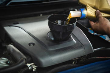 Auto mechanic pouring fully synthetic motor oil into the engine ,motor oil change service in garage...