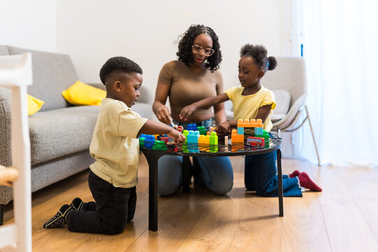 Mother and children playing with building blocks at home