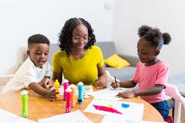 Mother supervising children drawing with dot markers at home