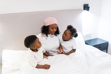 Obraz premium Mother with cancer talking to her children in bed, maintaining normality and family bonds