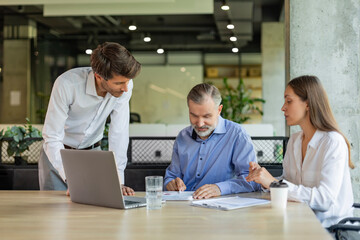 Successful businesspeople working in a coworking space working with laptop discussing strategy and...