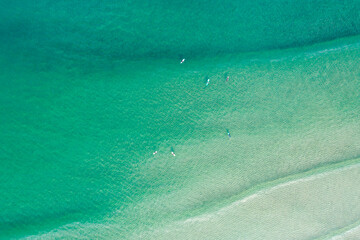 Obraz premium Serene Seascape with People on Surfboards Top Down Drone Shot of Surfers Waiting for Waves in a calm turquoise water sea