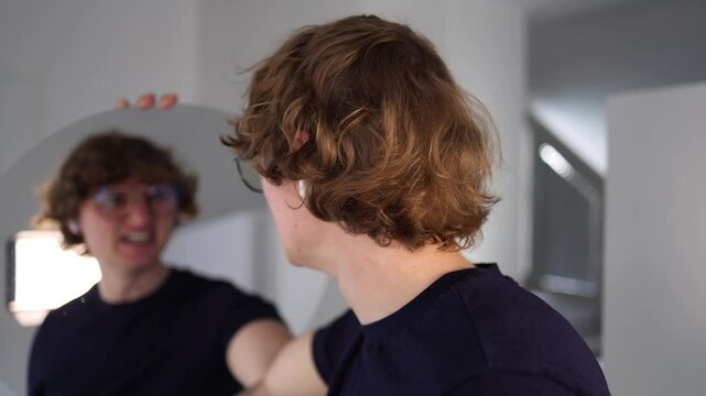 Young man points at his own reflection in the mirror with a surprised and slightly accusatory expression as if caught off guard or confronting himself about something unexpected