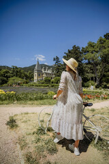 A woman in a white dress is riding a bicycle in a field