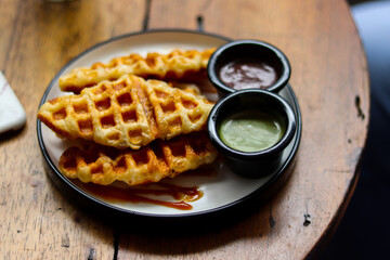 A plate of waffles with matcha sauce and chocolate sauce.