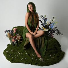 fantasy portrait beautiful female model wearing green fairy gown costume. sitting pose on moss...