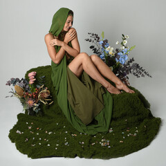 fantasy portrait beautiful female model wearing green fairy gown costume. sitting pose on moss...