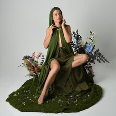 fantasy portrait beautiful female model wearing green fairy gown costume. sitting pose on moss...