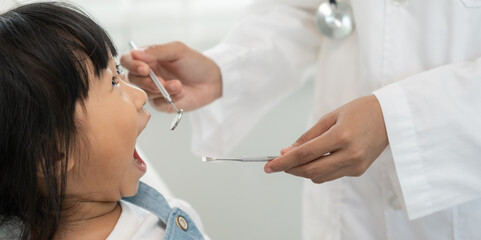Dentist or dentist treating or examining a little girl teeth, Child receiving treatment from...
