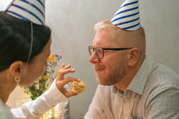 Birthday Party Cake Couple: Indoors, celebrating birthday with cake feeding; joyous moment.