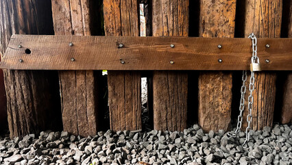 old wooden fence with chain and padlock on gravel ground - texture concept series