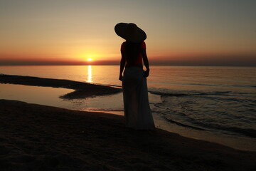 Fototapeta premium woman walking on the beach at sunrise
