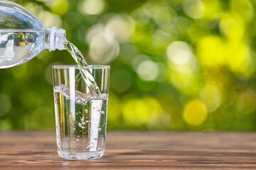 Drink water from plastic bottle pouring into glass on wooden table