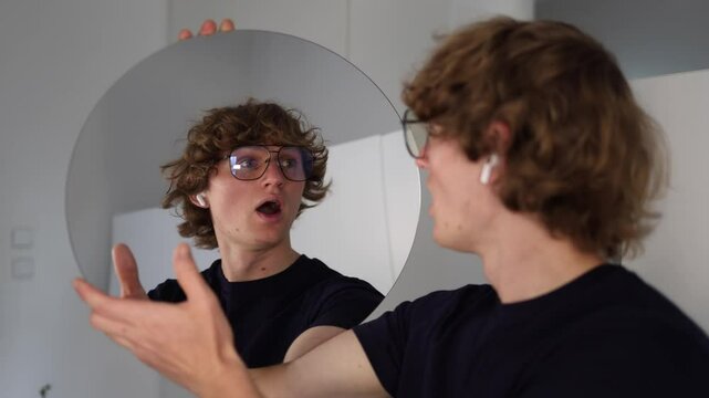 Man looks into the mirror with wide eyes and open mouth in a moment of sudden shock or realization as if something unexpected just hit him emotionally or mentally