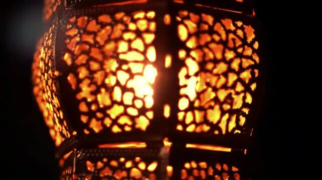 Lit metal lantern with intricate organicshaped cutouts glowing in the dark