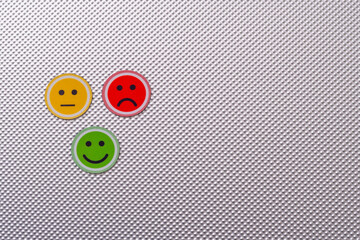 Three round emoji faces in red, yellow, and green representing sad, neutral, and happy emotions on...
