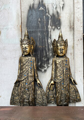 Two golden Buddha statues, crafted from wood and adorned with intricate details and blue glass...