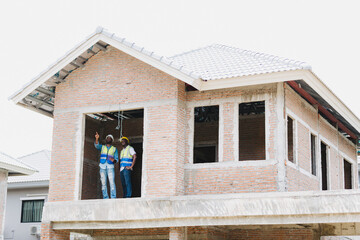 Two engineers in safety gear inspecting a building under construction. black engineers inspect ceiling infrastructure at a construction site