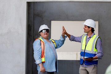 Construction team members wearing hard hats share a high five