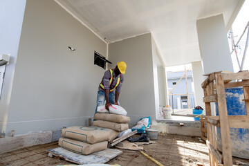 Worker is unloading the bags of cement an apartment is under construction, remodeling, renovation,...