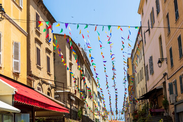 Southern street with colorful flags between historic houses France, Corsica, Ajaccio, 13 June 2025