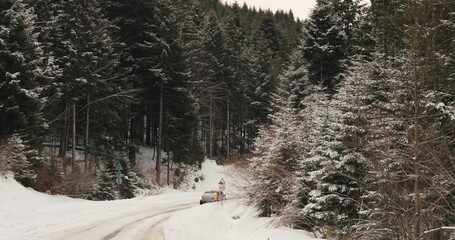 Aerial view of a winding snowy mountain road cutting through a dense winter forest. Mountain road...