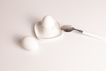 White eggs placed on a minimalist plate with a spoon, creating a simple yet elegant breakfast setting in soft natural light