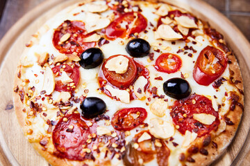 Pizza with salami and mozzarella cheese, jalapeno pepper and black olives. Wooden background. Soft focus. Close up.	