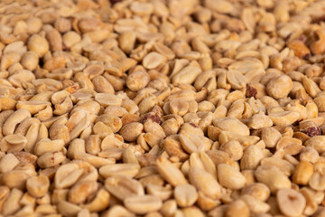 Close-up view of dry roasted peanuts on a flat surface showcasing texture and natural color variation in a bright environment