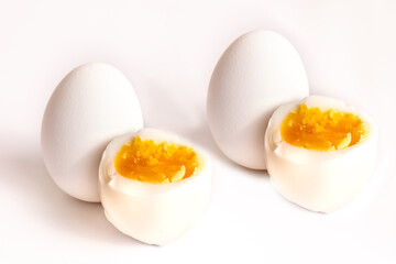 Perfectly boiled eggs cut in half showing bright yellow yolks on a white background ready for a healthy meal or snack