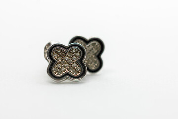 Pair of earrings with a diamond design. The earrings are silver and black. They are sitting on a white background.