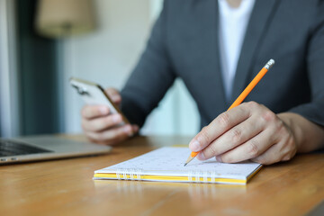 close up businessman hand use pencil to write or mark on important date of conference meeting manage timetable each day  in office private room for for planning work and life concept