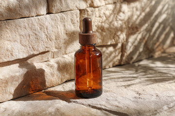 Amber glass dropper bottle standing on a stone surface with natural sunlight and shadows, ideal for skincare, cosmetics, or essential oils