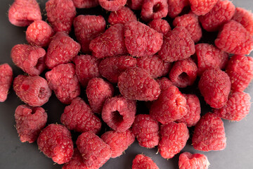 Freshly harvested raspberries arranged on a sleek dark surface, showcasing their vibrant color and...